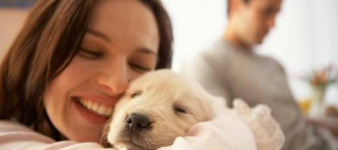 A happy woman holding a puppy.