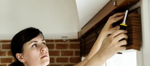 Woman putting up Venetian blinds