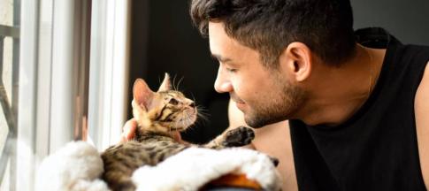 Image of a man looking at his kitten. 