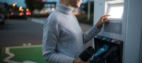 Image of a white woman charging her EV. 