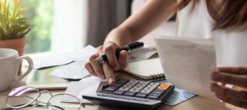 Woman sat at table budgeting with a calculator