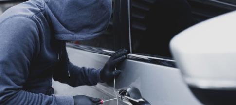 Person in mask and gloves breaking into car