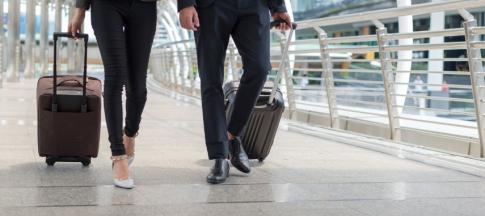 A businessman and businesswoman wheeling suitcases