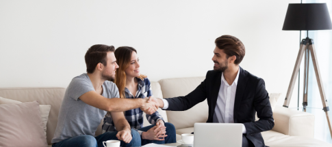 Man handing a set of keys to a couple, sat on sofa 