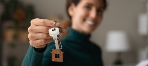 Woman holding a set of keys with a house keyring on it