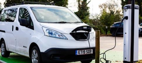 white electric van charging at station outside