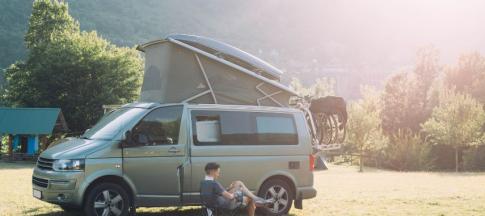 Man sat on camping chair beside campervan