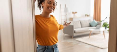 Woman in orange jumper opening the door to her apartment