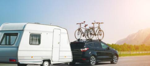 A car with two bikes secured on top towing a caravan