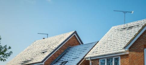Three terraced house roofs with snow on them 