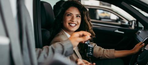 A woman sitting in a car being handed a car key
