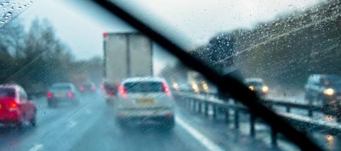 View from the front seat of a car on a rainy motorway, windscreen wiper in front