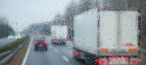 View through a rainy windshield of a lorry driving on a road
