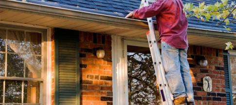 Man in a red shirt clearing a gutter