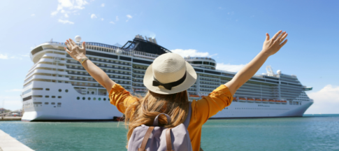 woman standing in front of docked ship arms in air