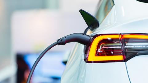 White electric car viewed from rear getting charged at electric charge point