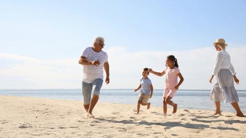 Children with grandparents spending time together on sea beach By New Africa